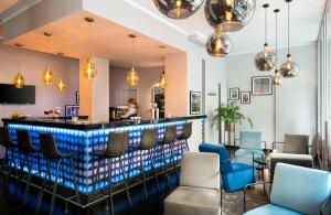 a bar in a restaurant with blue chairs and lights at Leonardo Hotel Berlin in Berlin