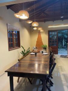 a large wooden table in a room with chairs and lights at Casa ao mar -Pousada Itapema in Itapema