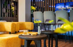 a waiting room with chairs and tables and flowers at Leonardo Royal Hotel Cologne Bonn Airport in Cologne