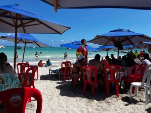 a group of people sitting under umbrellas on a beach at Flats Raízes da Barra - Terceiro in Maragogi