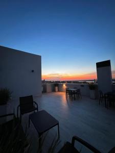 a rooftop patio with chairs and tables at sunset at The One DownTown Costanera in Asunción