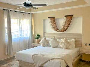 a bedroom with a white bed with a ceiling fan at Quinta Nina Playa del Carmen - Solo Adultos in Playa del Carmen +22 photos