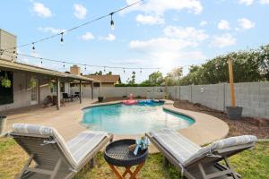 a backyard with a swimming pool and two chairs at Spacious Scottsdale Getaway with Pool in Tempe
