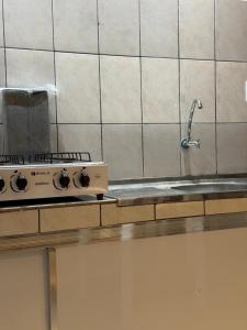 a kitchen counter with a stove and a sink at Apartamento Estúdio in Macapá