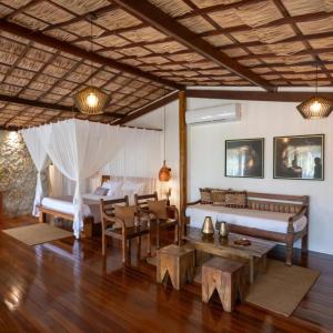 a bedroom with a bed and a table and chairs at Hara Pousada e SPA in São Miguel do Gostoso