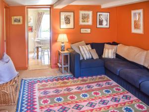 a living room with a blue couch and an orange wall at Green Farm Cottage in Redgrave