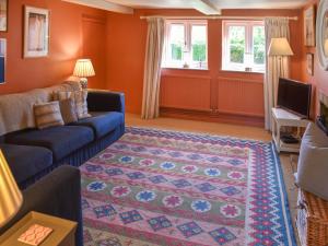 a living room with orange walls and a blue couch at Green Farm Cottage in Redgrave