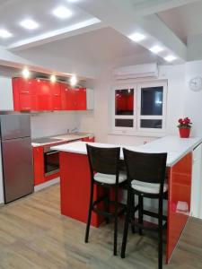 a kitchen with red cabinets and two chairs at a counter at Centro apartman 3 in Pančevo