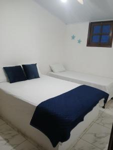 a white bed with a blue blanket on it at ElRancho Suites in Itaparica