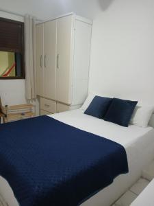 a bedroom with a large white bed with blue pillows at ElRancho Suites in Itaparica