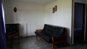 - un canapé en cuir noir dans un salon avec une télévision dans l'établissement Cabañas El Amanecer, à El Calafate