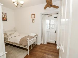 a white bedroom with a bed and a window at Sheepwash Barn in Freshwater