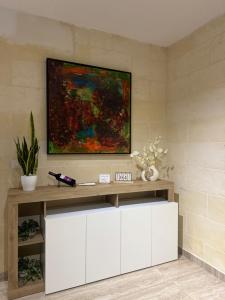 a painting hanging on a wall with a white table at Dar il-Wied in Għajn il-Kbira