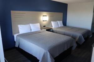 two beds in a hotel room with blue walls at legacy inn paducah in Paducah