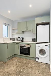 a kitchen with green cabinets and a washer and dryer at South Dublin Studio Apartment in Dublin