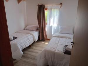 two beds in a room with a window at Cabañas del Oeste in San Carlos de Bariloche