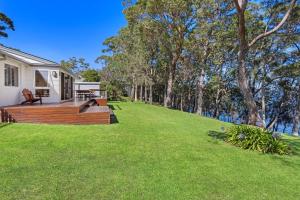 a house with a large yard next to the water at Serenity - Pet Friendly with Spa & Waterfront in Sanctuary Point