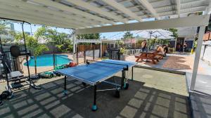 a ping pong table on a patio next to a pool at Somewhere To Stay Backpackers in Brisbane