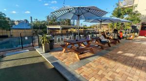 a group of people sitting at picnic tables under umbrellas at Somewhere To Stay Backpackers in Brisbane