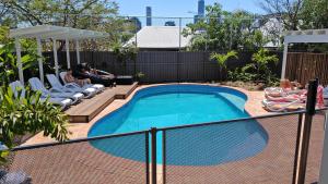 a swimming pool with two people sitting on chairs next to it at Somewhere To Stay Backpackers in Brisbane +9 photos