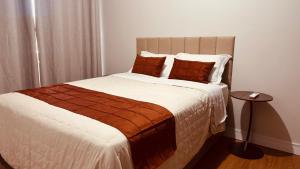 a bedroom with a large bed with brown pillows at Apartamento com ar condicionado e lava e seca in Cascavel