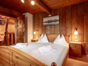 a bedroom with a bed with white sheets and wooden walls at Weberhäusl am Penningberg in Hopfgarten im Brixental