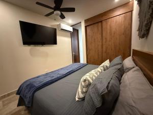 a bedroom with a bed with a flat screen tv on the wall at Stylish 1BR Ocean View near 5th Ave in Playa del Carmen +14 photos
