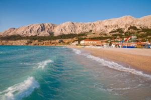 a beach with houses and mountains in the background at Apartment Malinska 44 in Malinska