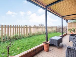 a patio with chairs and a table and a fence at The Barn At Whitefields in Walcot