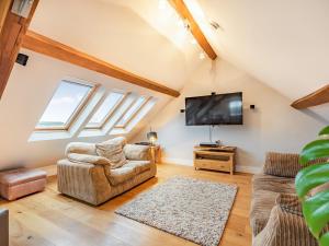 a living room with two chairs and a flat screen tv at The Barn At Whitefields in Walcot