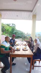a group of people sitting around a table eating food at Tama View in Tuktuk Siadong