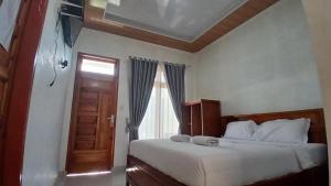 a bedroom with a bed with a door and a window at Tama View in Tuktuk Siadong