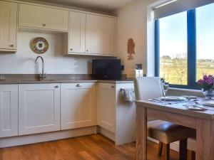 a kitchen with white cabinets and a table and a window at The Wolfs Den - Uk49083 in Winewall