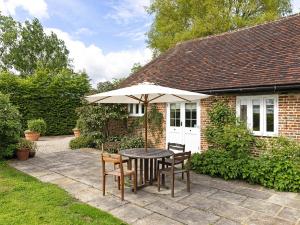 a table and chairs with an umbrella in front of a house at Leacon Hall Lodge in Orlestone