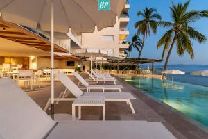 a pool with chairs and umbrellas next to a building at PANAREA - Luxury Beachfront Condos in Bucerias in Bucerías