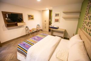 a bedroom with a bed and a tv and a desk at Nativo Hotel in Popayan