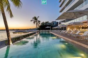 a pool at the beach with chairs and umbrellas at PANAREA - Luxury Beachfront Condos in Bucerias in Bucerías