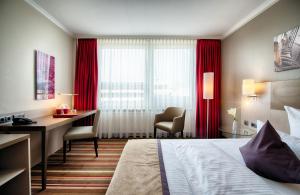 a hotel room with a bed and a desk and a window at Leonardo Hotel Hamburg City Nord in Hamburg