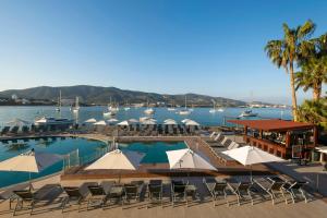 a pool with chairs and umbrellas and boats in the water at Leonardo Royal Hotel Mallorca in Palmanova