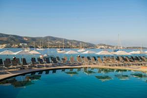 a pool with chairs and umbrellas next to the water at Leonardo Royal Hotel Mallorca in Palmanova