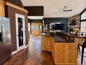a large kitchen with wooden floors and a stainless steel refrigerator at Elegant Blackwood Grove by Casa Oso in Mariposa
