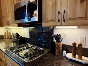 a kitchen with a stove and a microwave at Elegant Blackwood Grove by Casa Oso in Mariposa