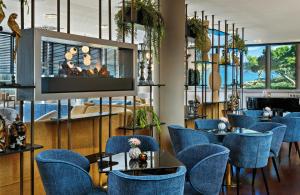 a restaurant with blue chairs and a flat screen tv at Leonardo Hotel Esslingen in Esslingen +58 photos
