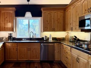 a kitchen with wooden cabinets and a sink and a window at Elegant Blackwood Grove by Casa Oso in Mariposa