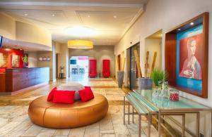 a lobby with a table and a large ottoman at Leonardo Hotel Karlsruhe in Karlsruhe