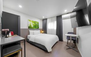 a bedroom with a white bed and a desk and a table at Songdo The Seoleim Hotel Stay in Incheon