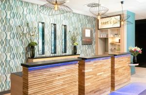 a bar in a salon with a blue wall at Leonardo Hotel Hamburg Altona in Hamburg