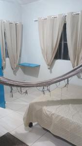 a room with a table with curtains and a bed at Ap do Jhone in Canoa Quebrada