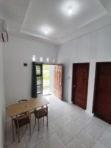 a dining room with a wooden table and two doors at Hotel Sarijadi Pangururan in Pangururan