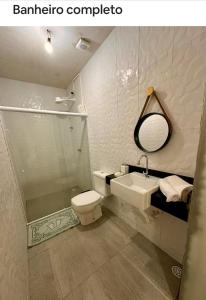 a bathroom with a toilet and a sink and a mirror at Flats Raízes da Barra - Terceiro in Maragogi